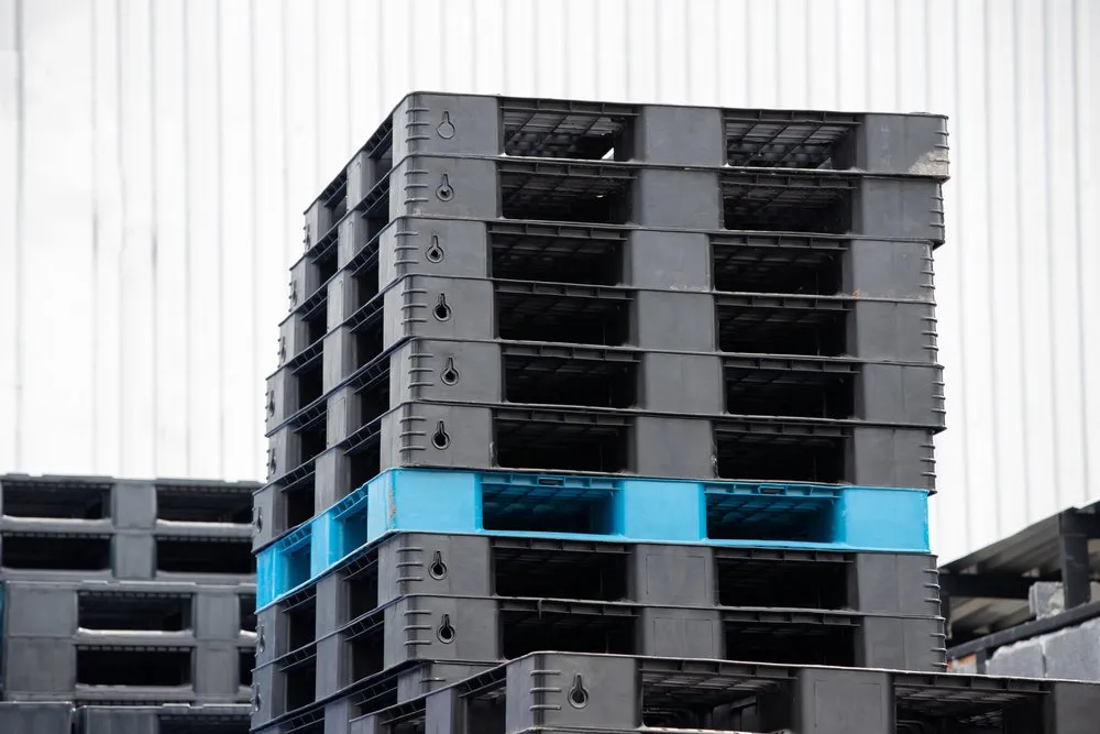 Pilhas de pallets plásticos empilhados em ambiente industrial, ilustrando o que é pallet na logística.