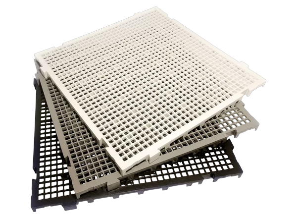 Três placas de piso plástico modular empilhadas nas cores branca, cinza e preta